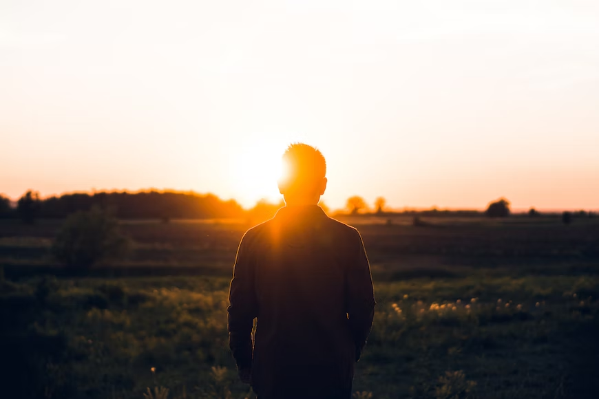 Person standing and looking into a sunset