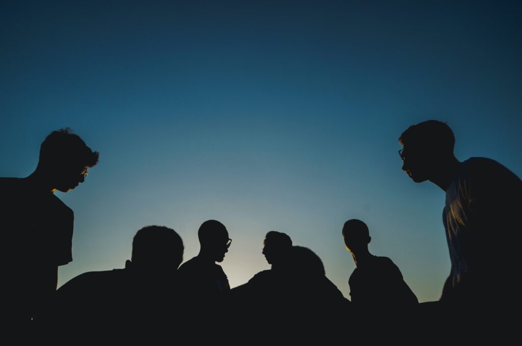 Silhouette of a group of men talking, with a dark blue night sky behind them